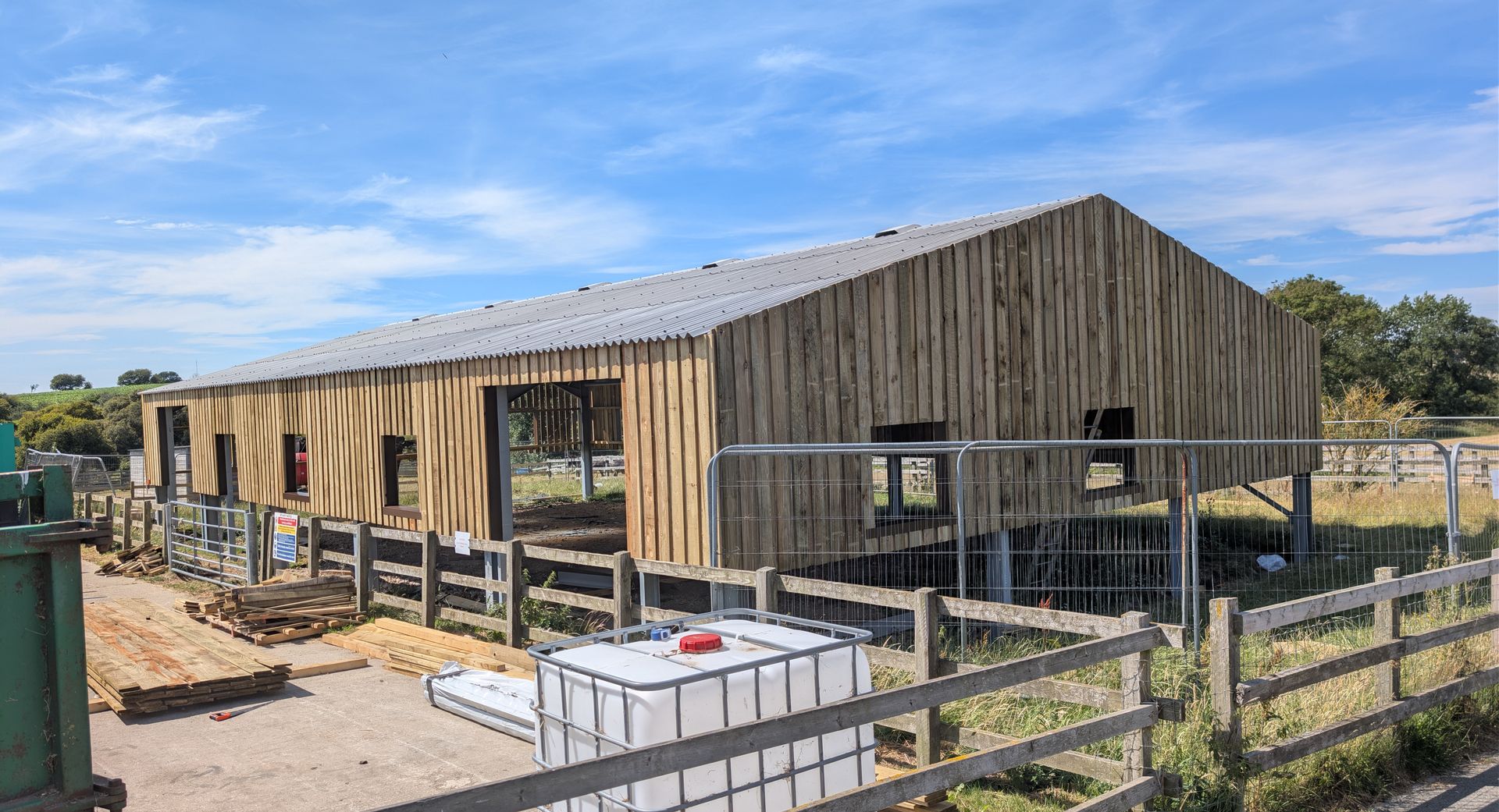 a barn with cladding at the top and open sides. It looks like a construction site. 
