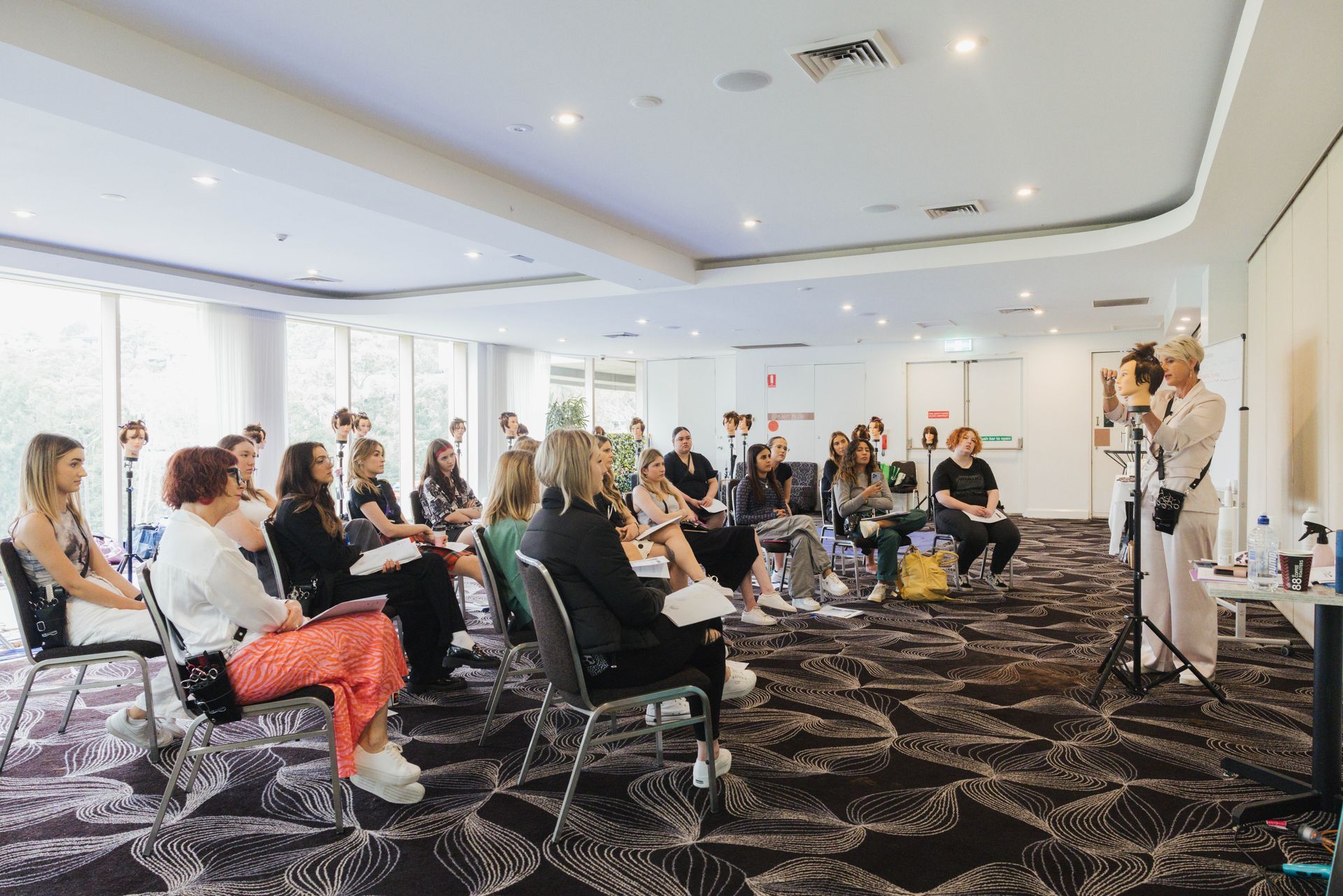 Scissor Licence students seated at a workshop watching a demonstration on a manneqin.