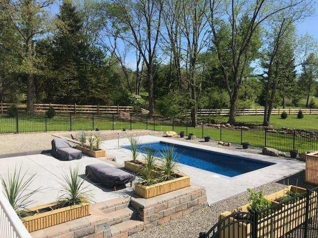 Backyard pool with stone patio, built-in planters, and lounge chairs surrounded by trees