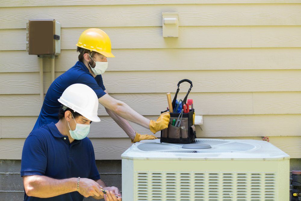 Two Air Conditioner Workers Service Outside — South Bend, IN — Ernsperger Air Conditioning & Heating Inc