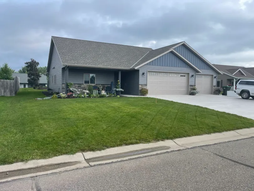 Suburban house with a large front lawn, two-car garage, and cloudy sky.