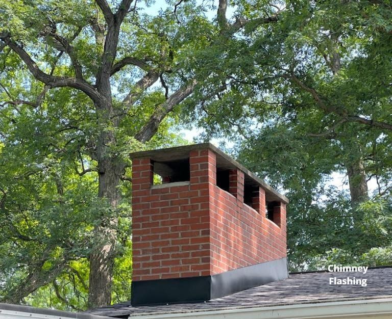 A brick chimney on top of a roof with trees in the background.