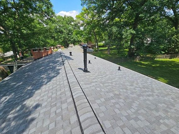 A roof with a chimney on it and trees in the background.