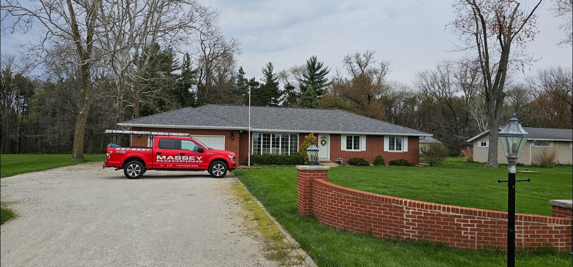 A red truck is parked in front of a brick house.