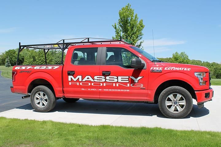 A red massey roofing truck is parked on the side of the road.