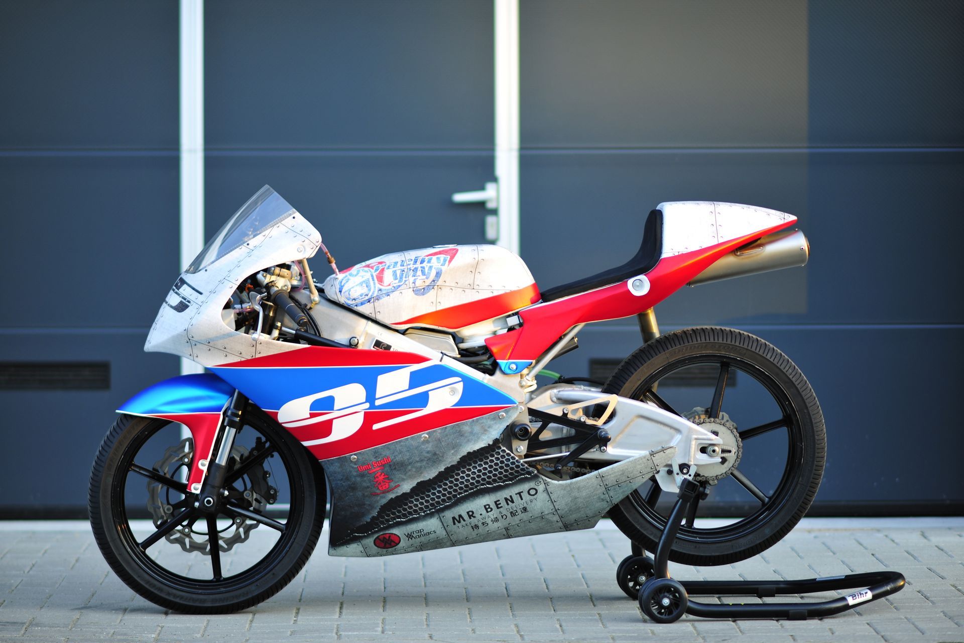 Sport motorcycle, white, blue, and red Crome wrap with number 93 livery, parked on stand outside  Wrap Maniacs workshop.