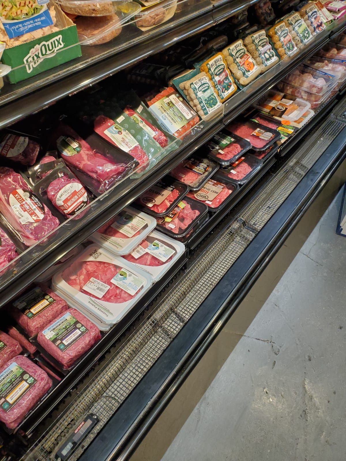 Meat products packaged in a grocery store refrigerated deli case.