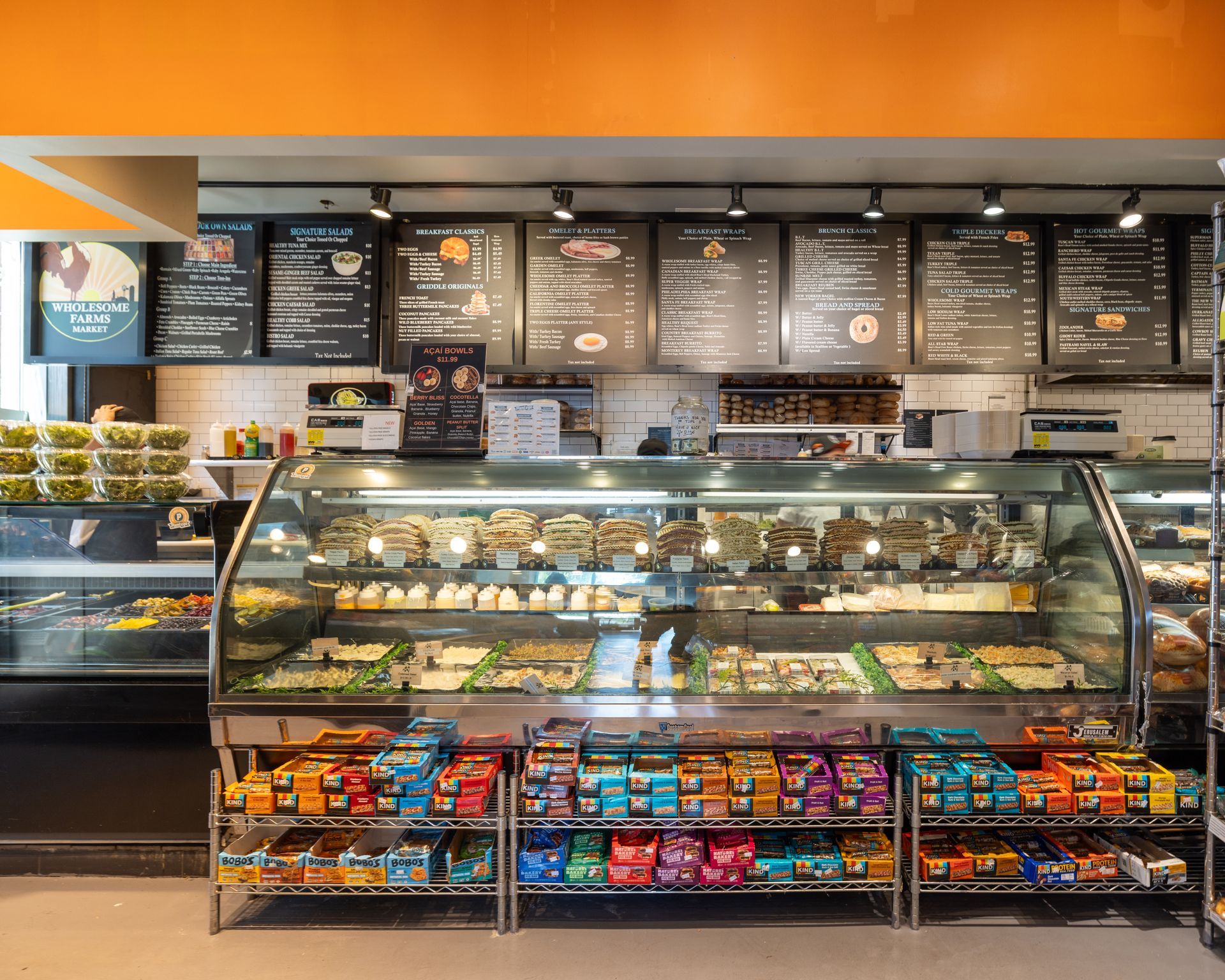 Coffee shop counter with pastry display case, menu boards, and snacks behind glass.