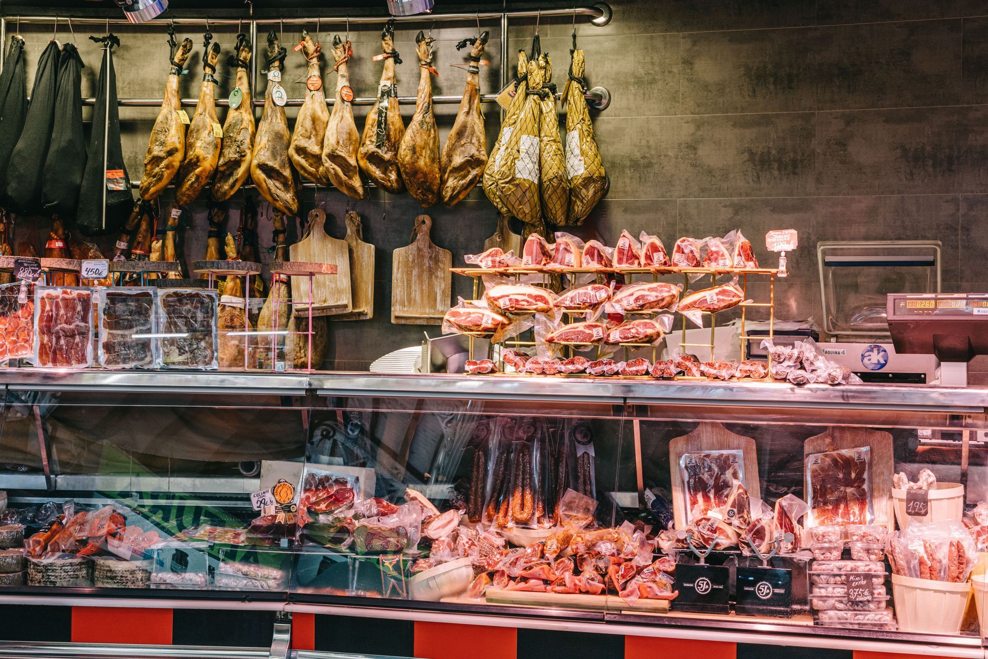 Butcher shop display with hanging cured meats and trays of assorted raw meat under glass counters