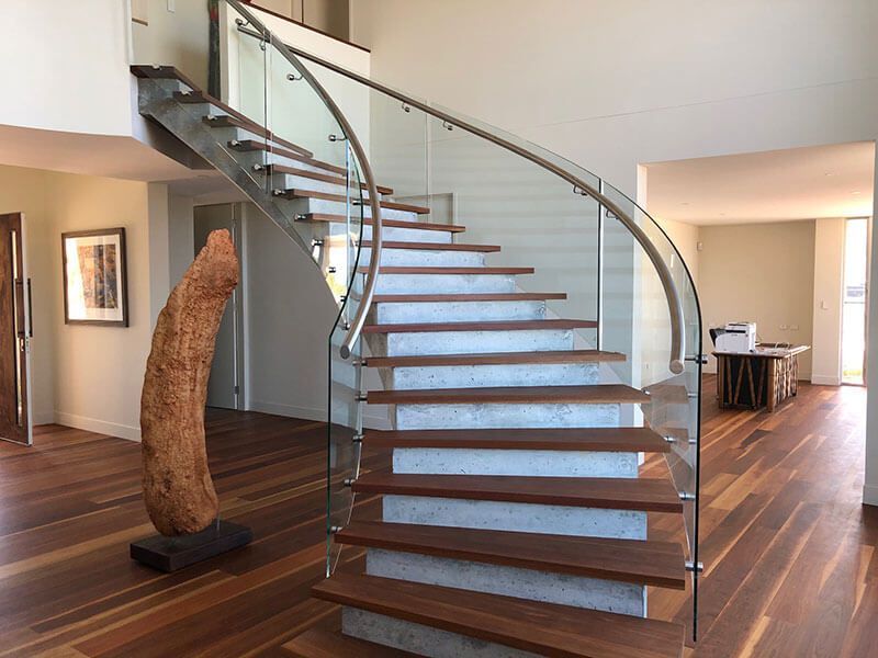 A Curved Staircase With A Glass Railing In A Living Room  — Star Glass Design Pty Ltd in Mayfield, NSW