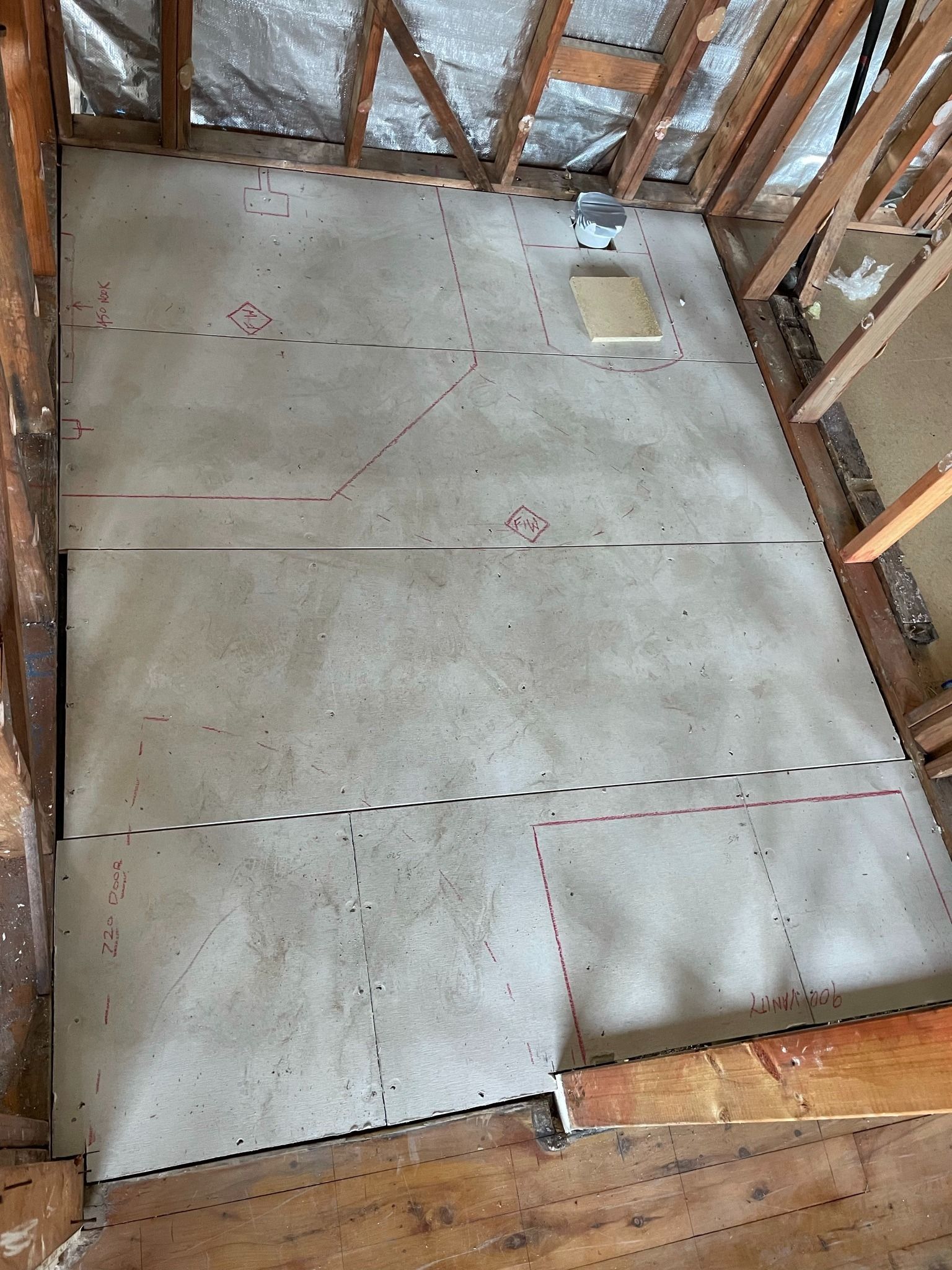 Concrete slab floor with plumbing rough-in inside an unfinished framed room