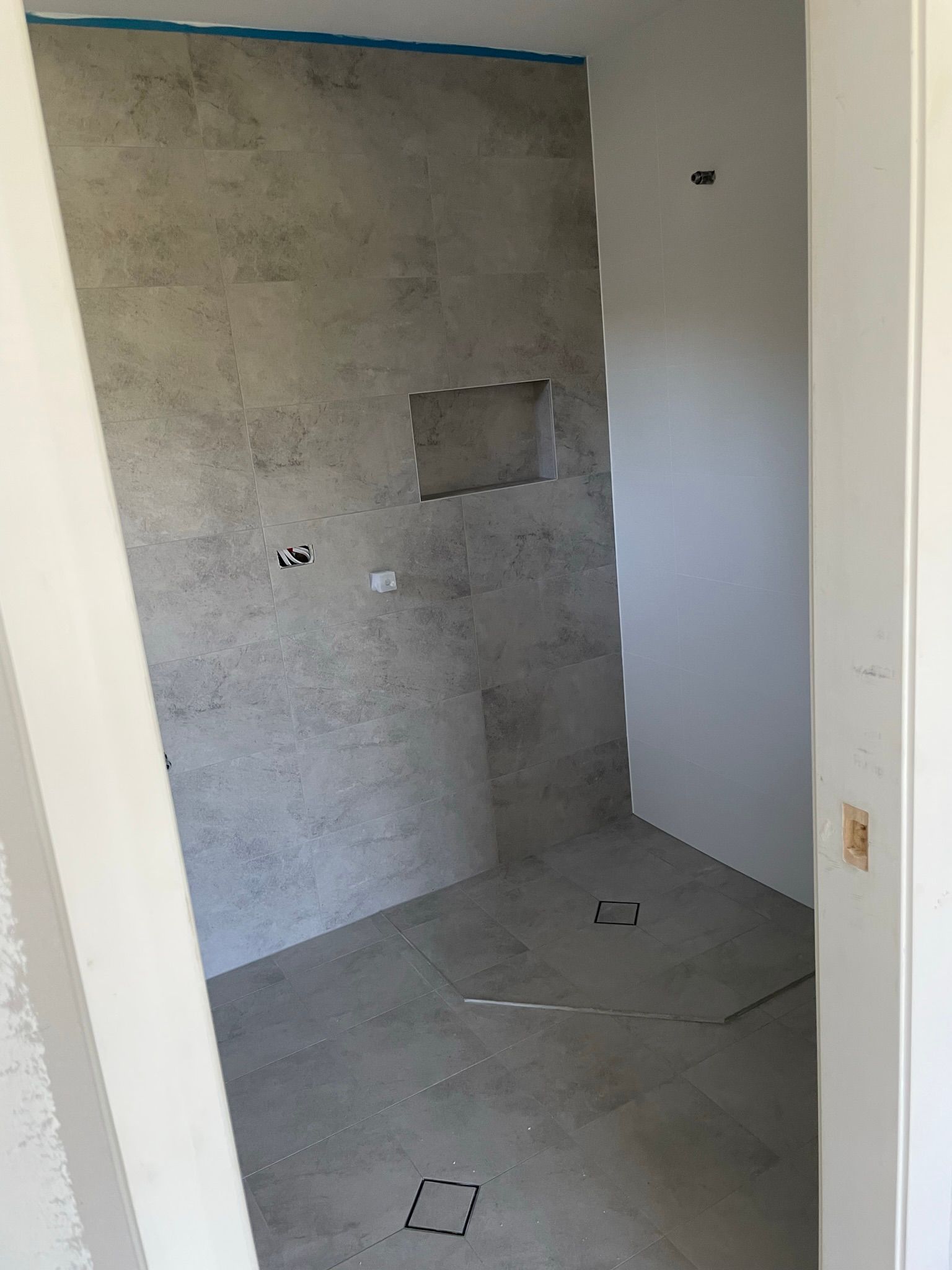 Empty unfinished room with gray walls, tiled floor, and a small wall cutout.