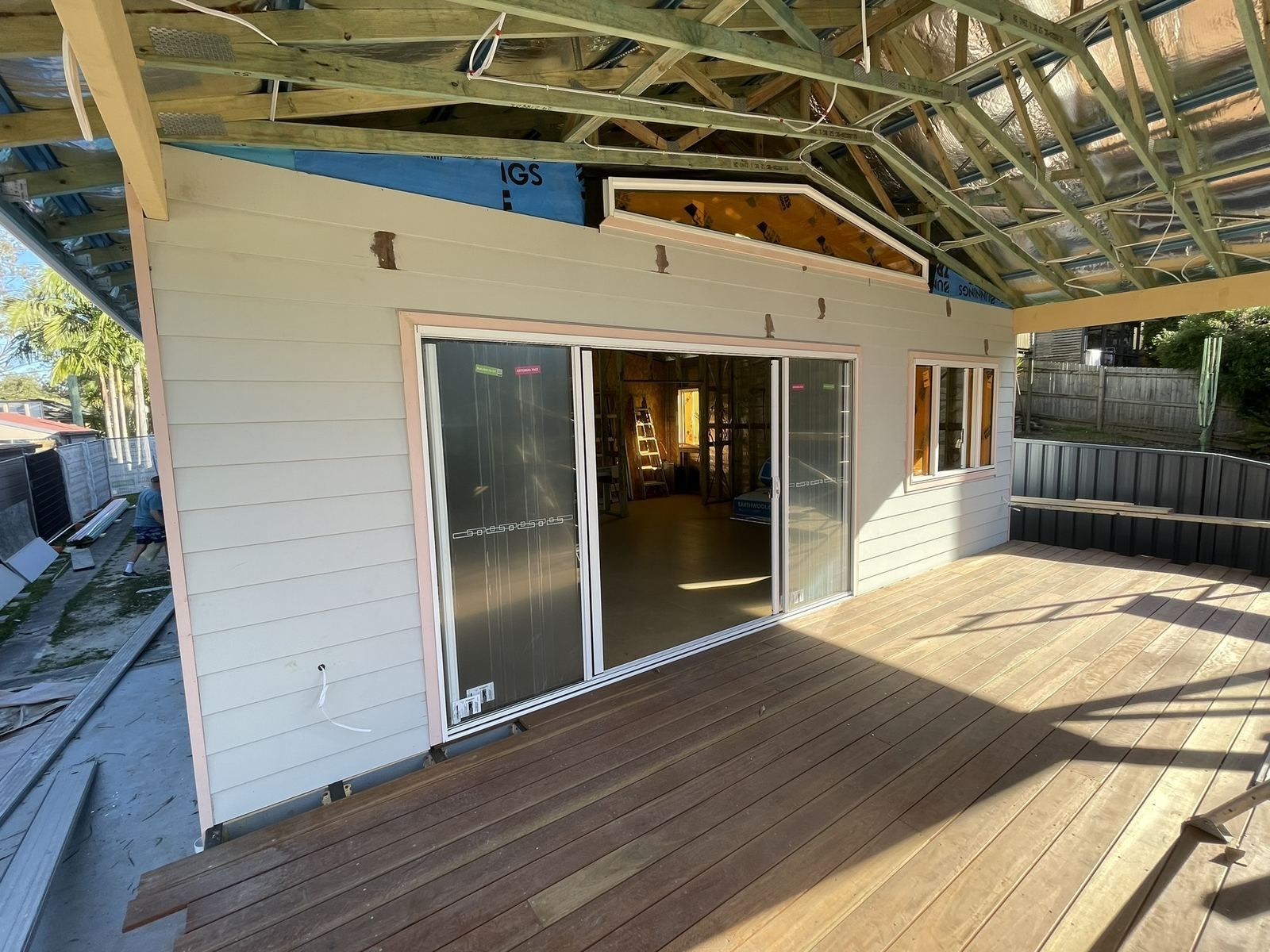 White house exterior with sliding glass doors opening onto a wooden deck under a covered roof