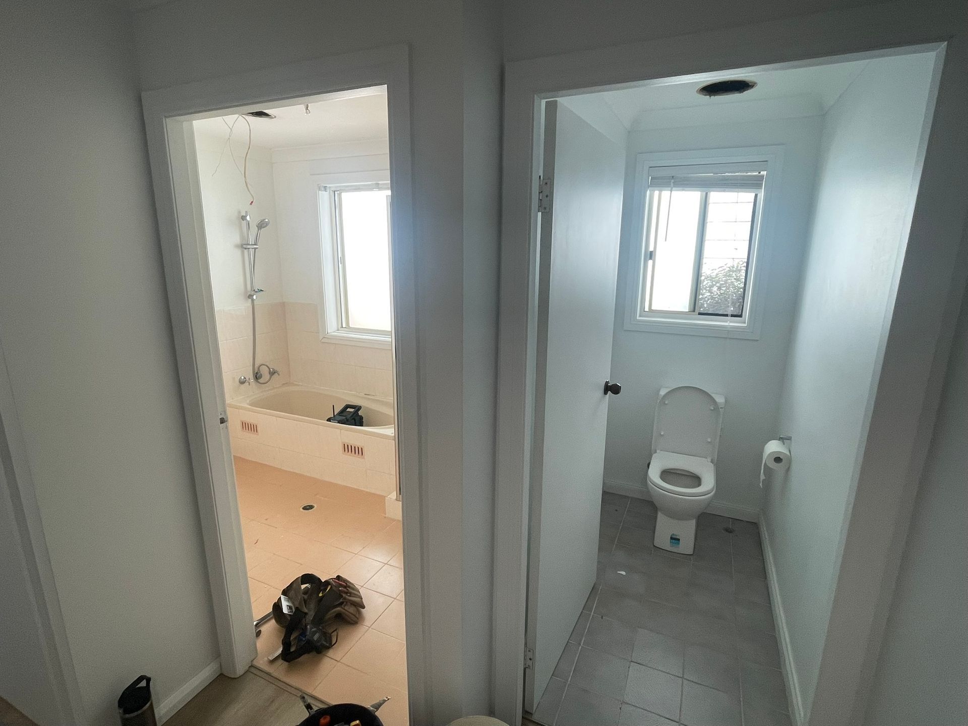 Bathroom hallway with two open doorways: a bright tiled bathroom and a small toilet room.