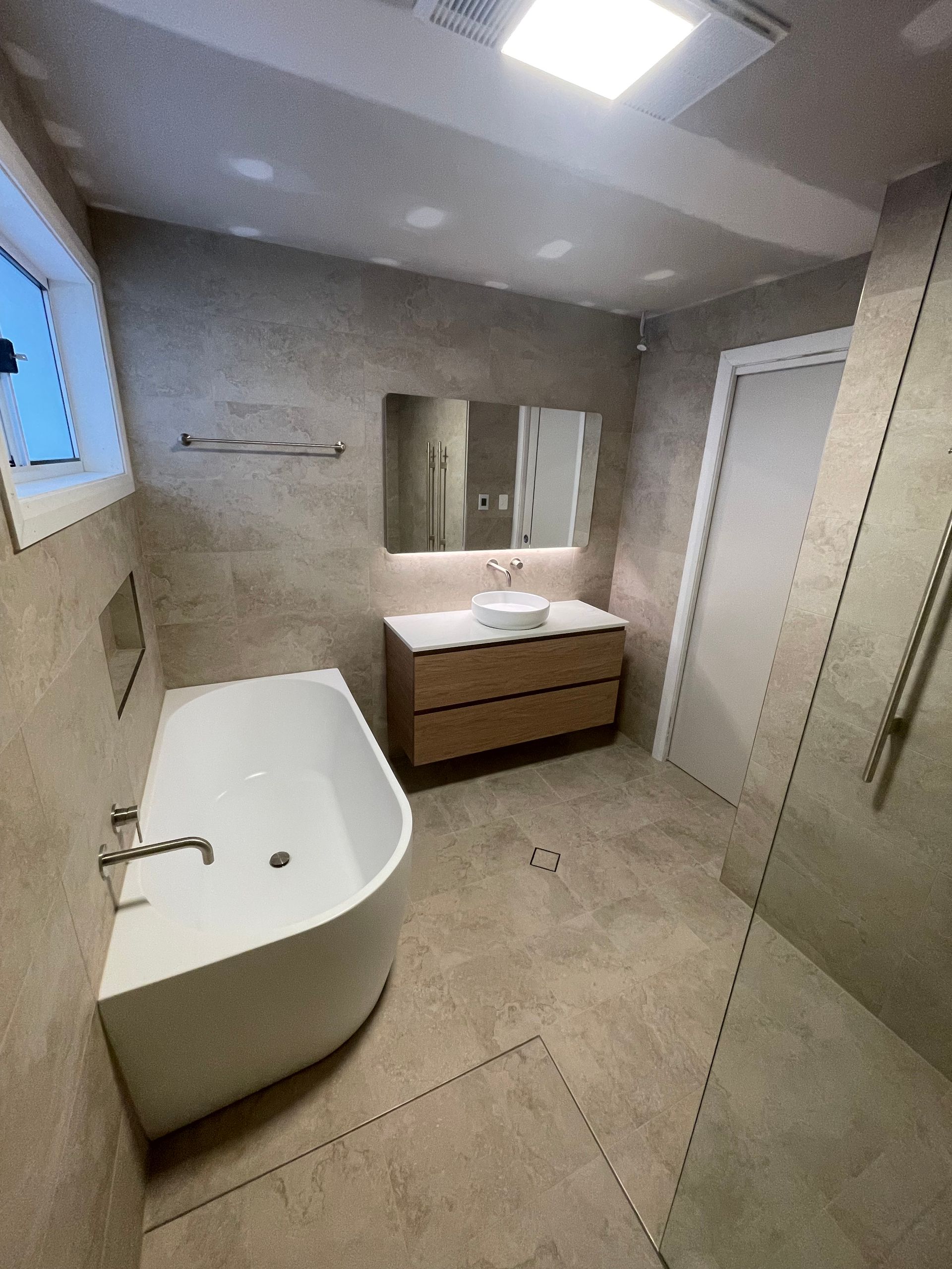 Modern bathroom with bathtub, double vanity, large mirror, shower, and tiled walls and floor