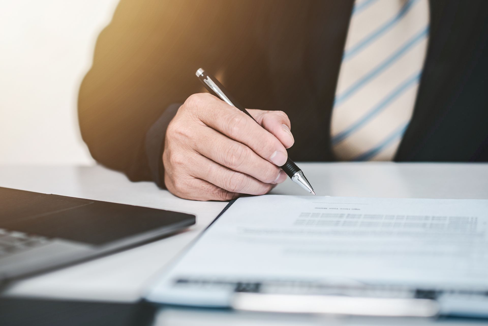 Businessman in suit signing legal document with a pen at a desk