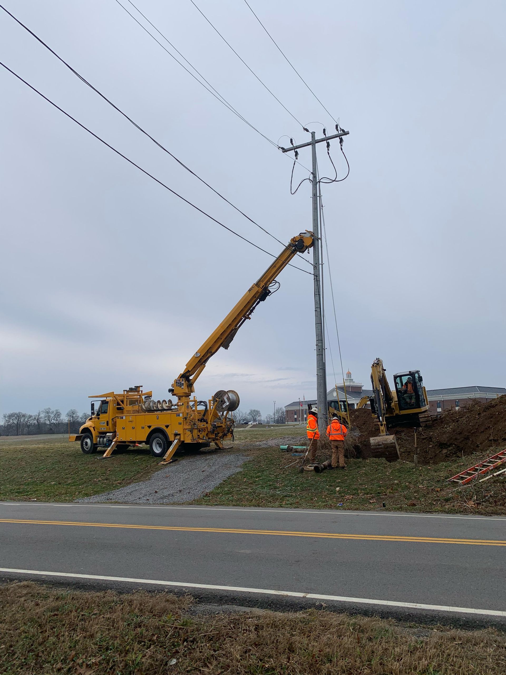 A yellow truck with a crane attached to it is working on a power line