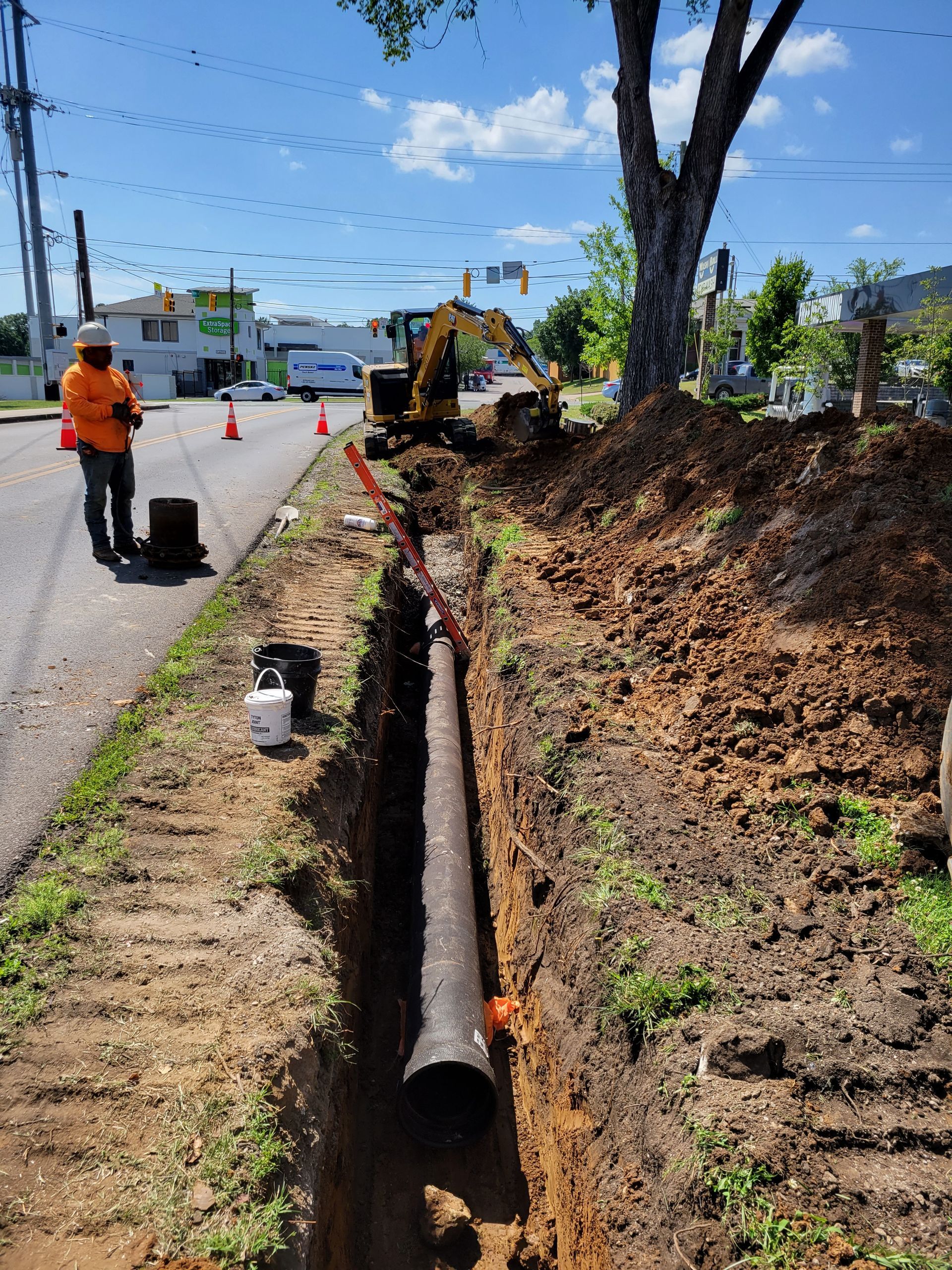 A man is standing next to a large pipe in the dirt