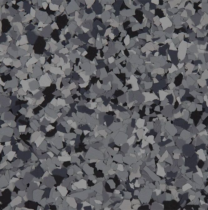 A texture of small, overlapping grey, charcoal, and white vinyl paint flakes used for garage floor coatings.