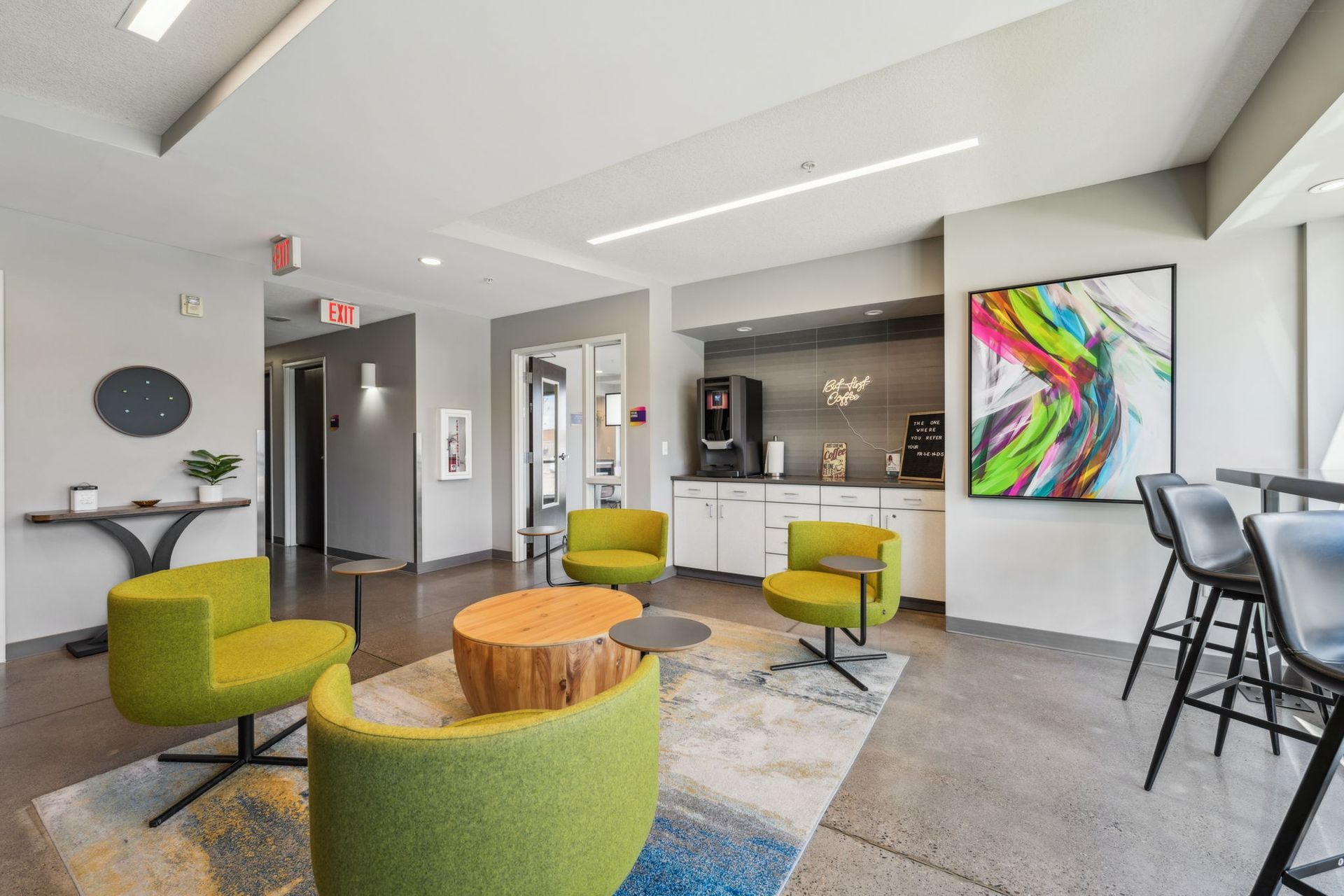 Lobby area with coffee station and colorful green chairs at Spectrum Apartments in Minneapolis