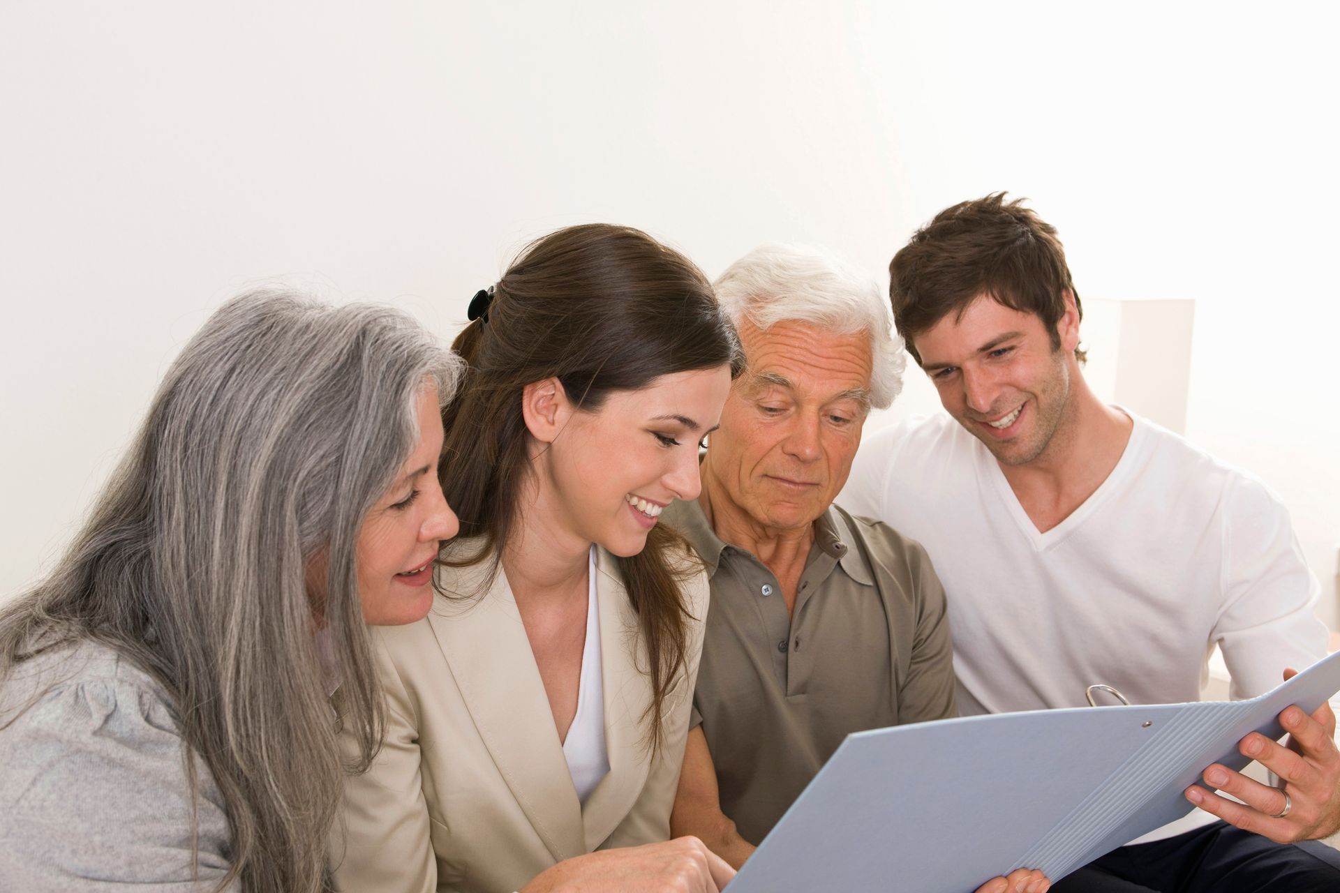 Four people gathered around a laptop, smiling and looking at the screen.