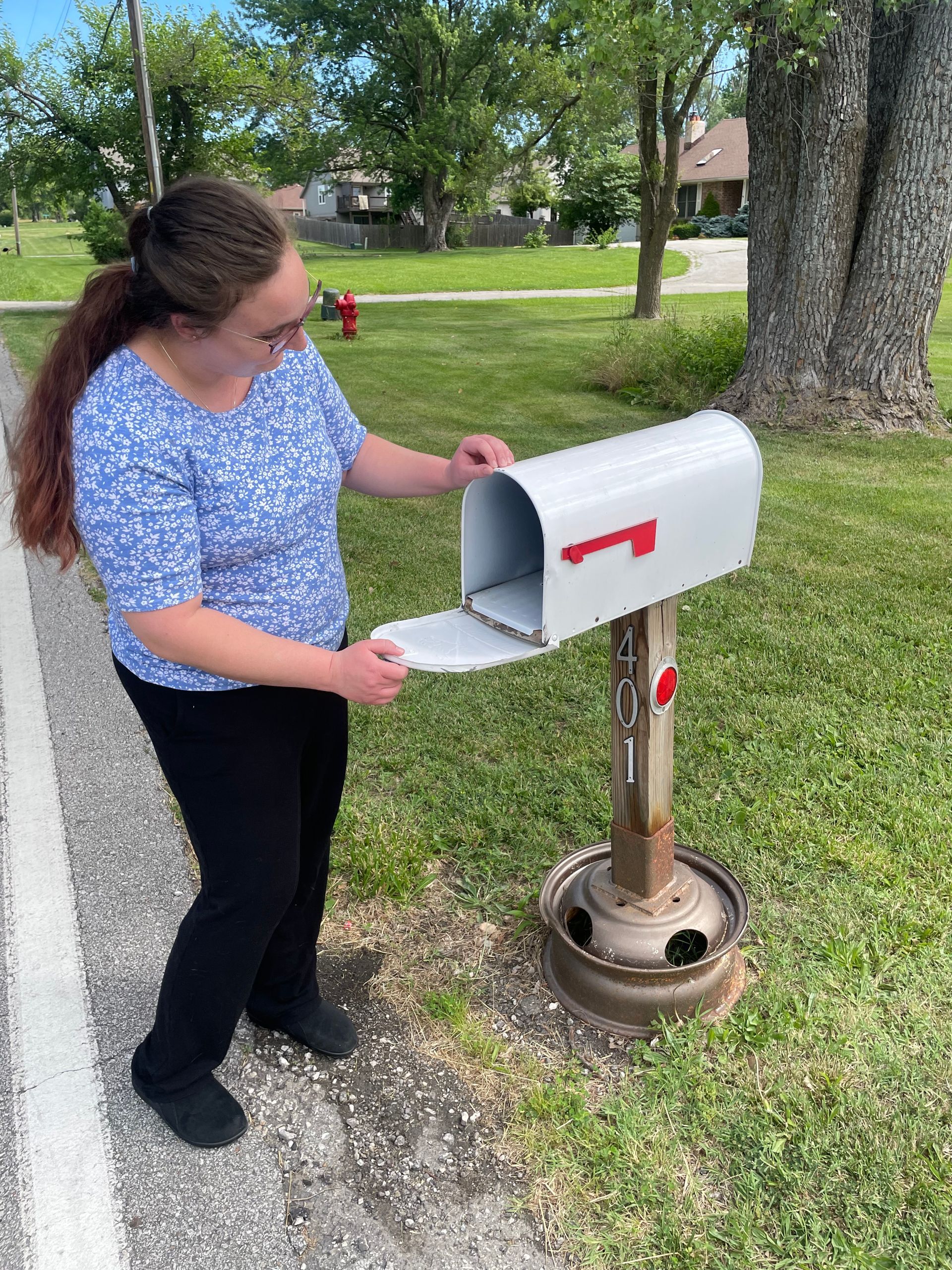 A woman is putting a letter in a mailbox.