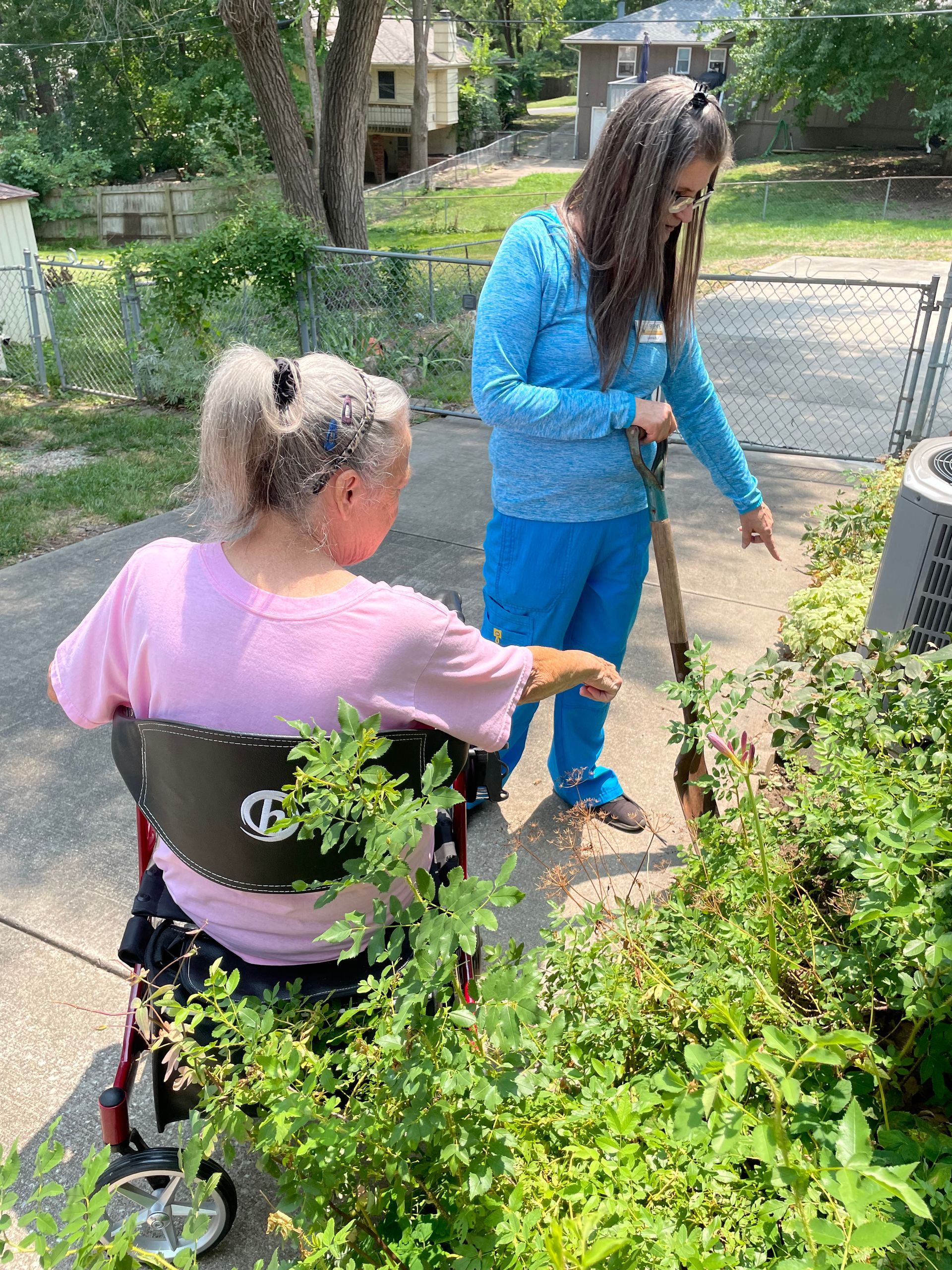 A woman in a wheelchair is standing next to a woman in a blue shirt.