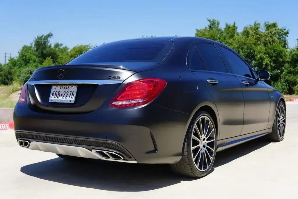 A black mercedes benz is parked on the side of the road