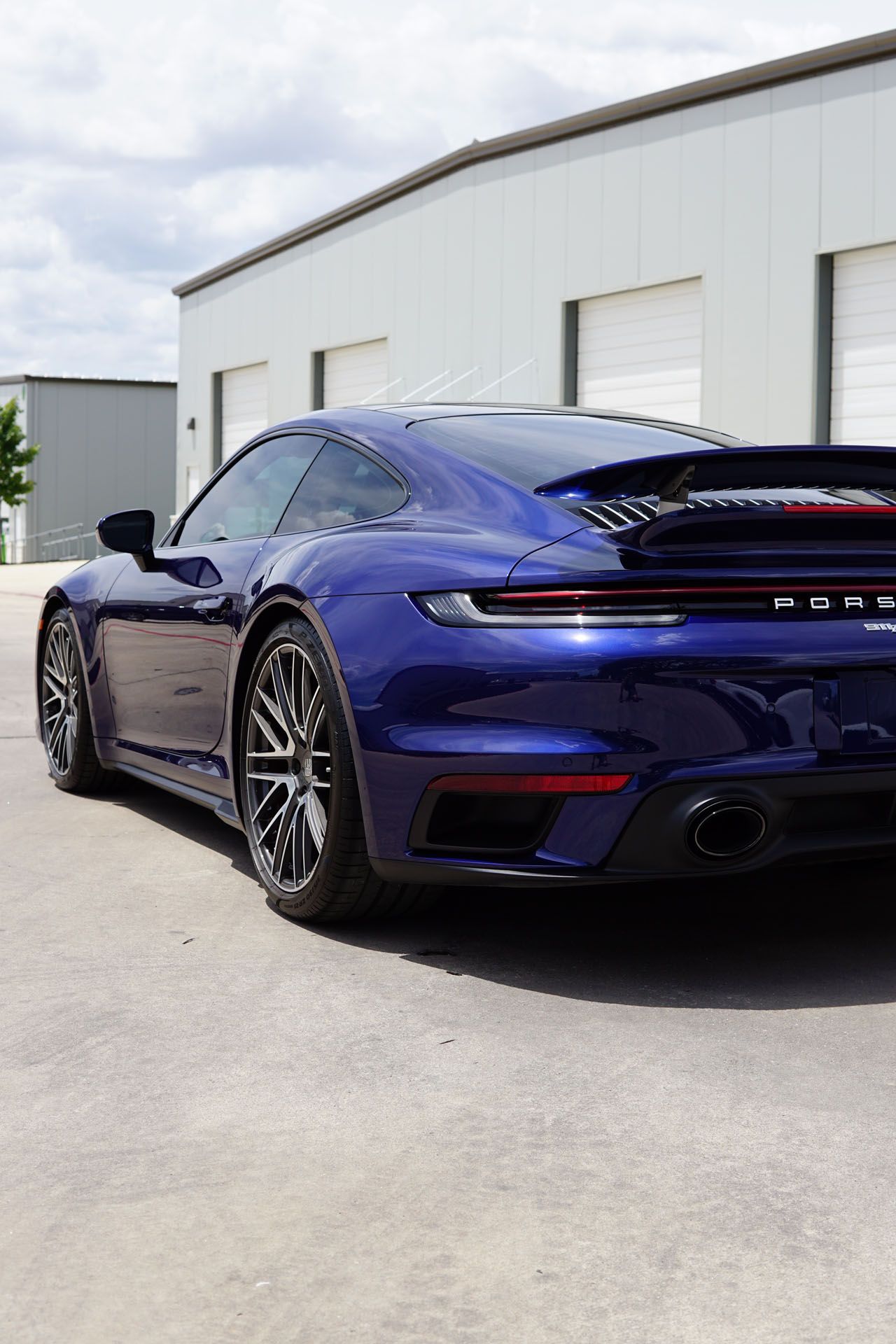 A blue porsche 911 turbo is parked in a parking lot.