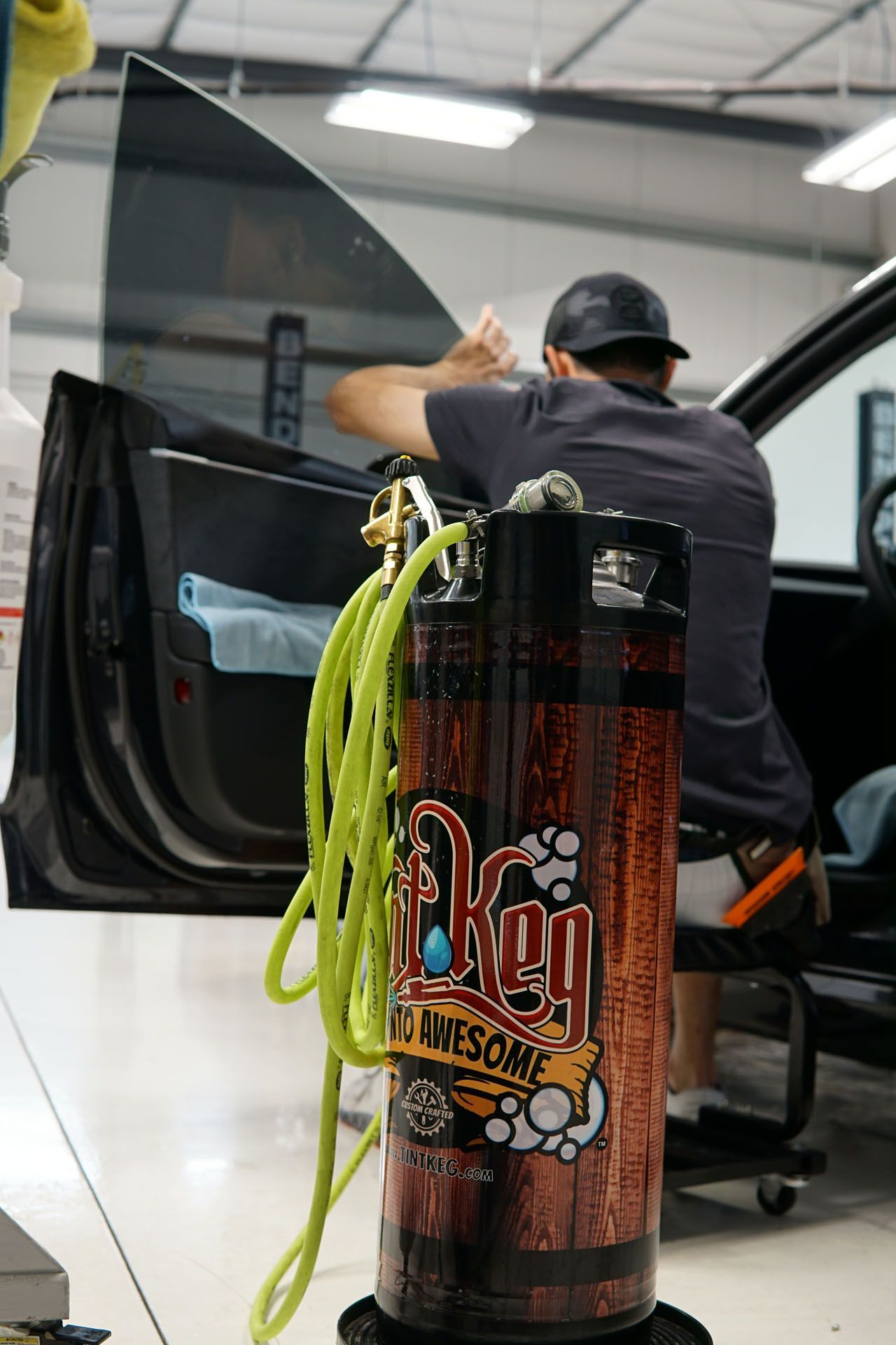 Person applying tint to car window, with equipment in front.