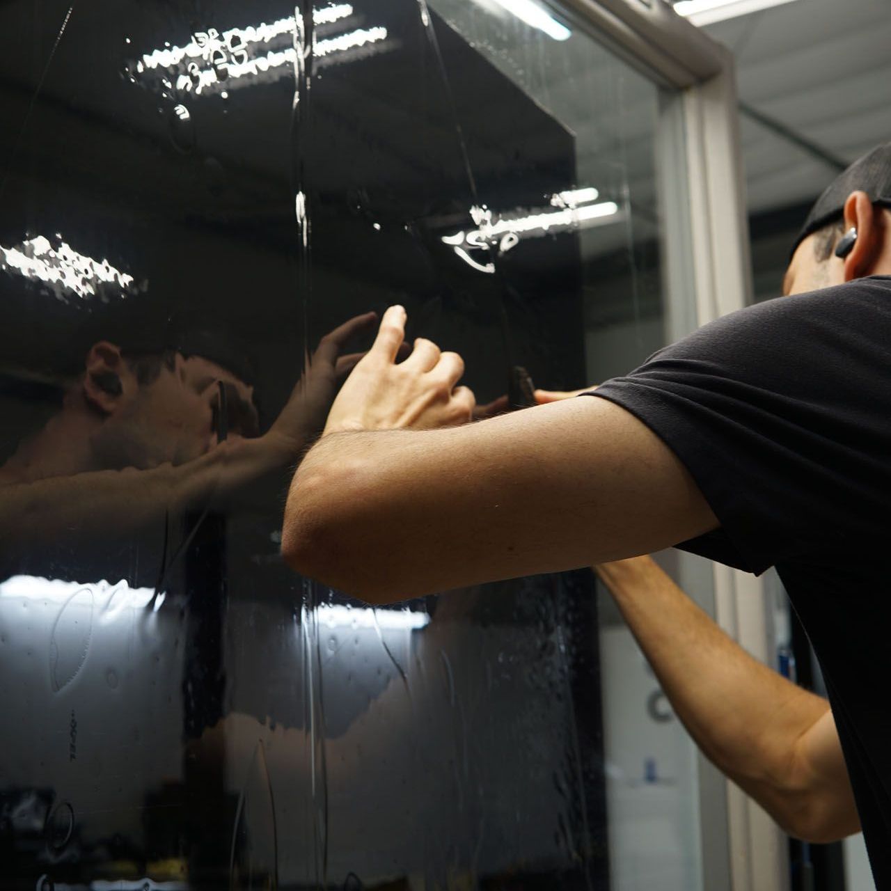 A man is cleaning a car window with a cloth