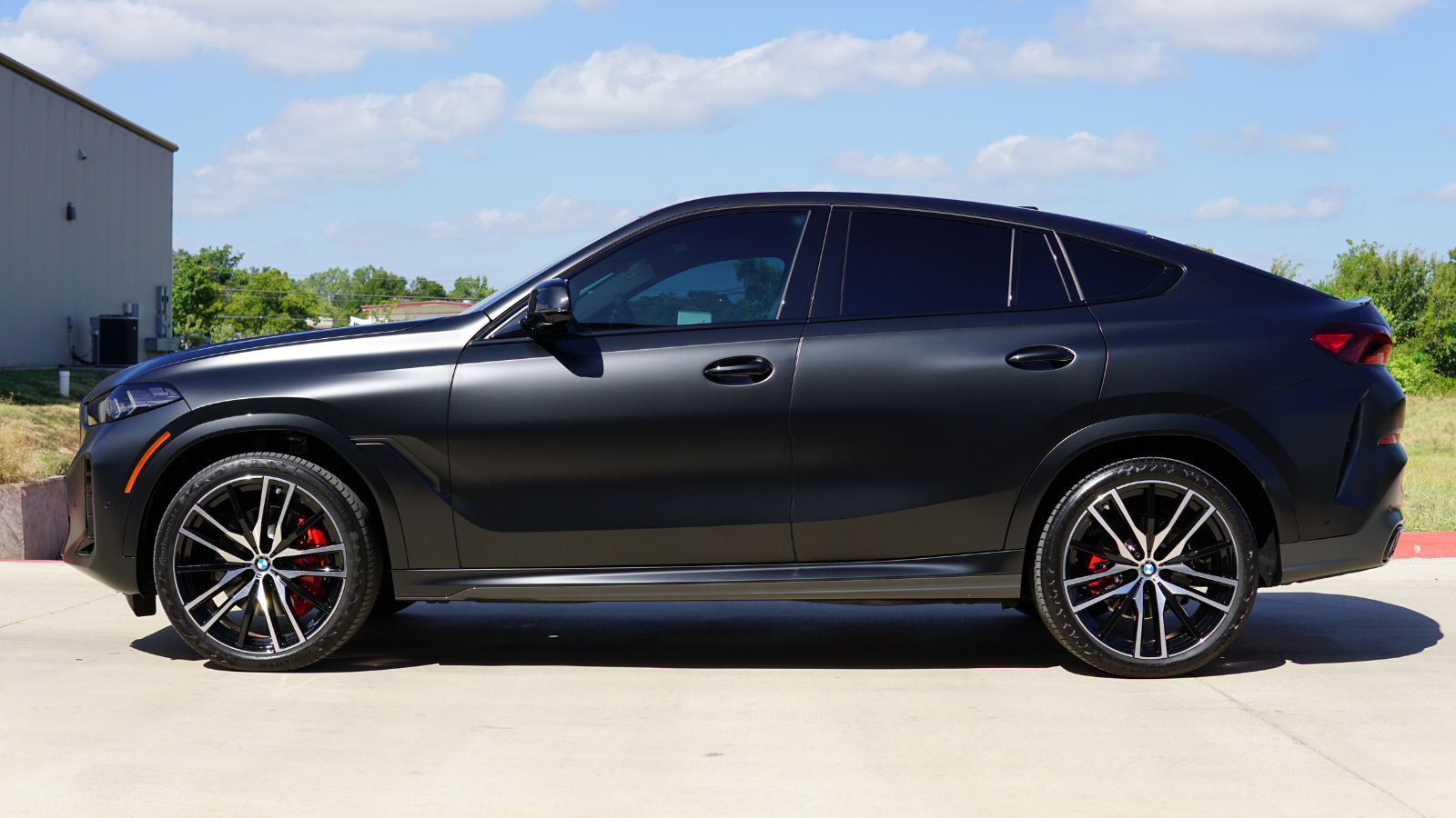 A black bmw x6 is parked on the side of the road.