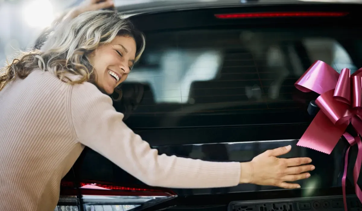 Woman hugging new car with a bow on it