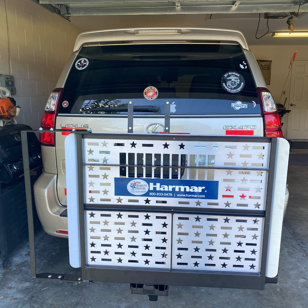 White SUV parked in a garage with a silver cargo carrier bearing a Harmar sign on the back.