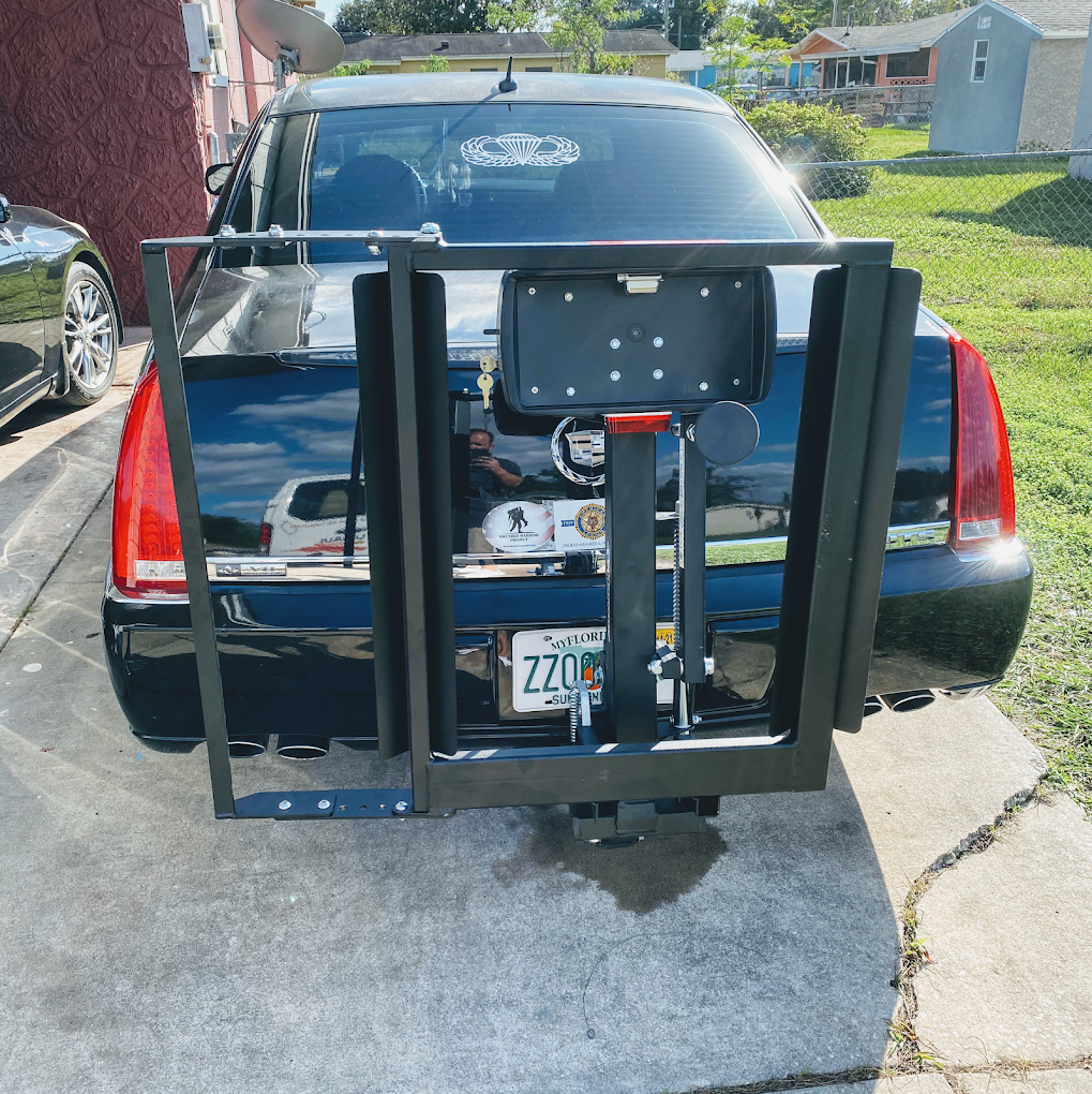 Black car with a rear-mounted wheelchair lift parked in a driveway