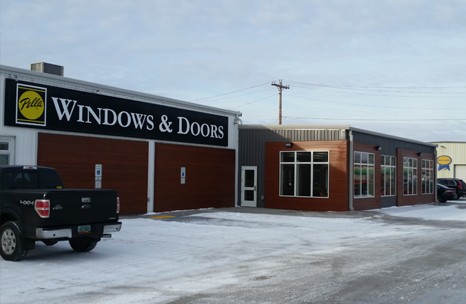 A truck is parked in front of a building that says windows and doors