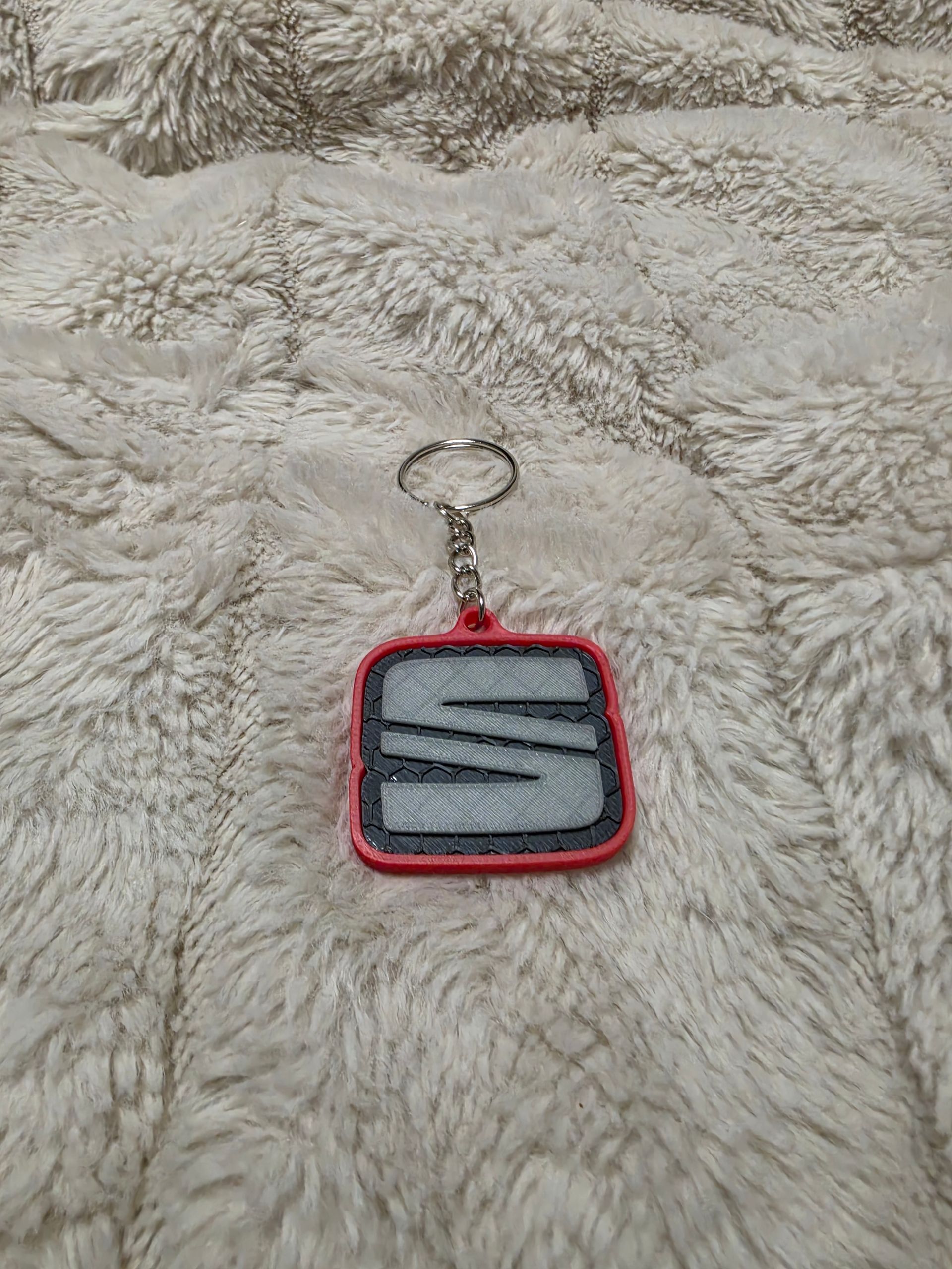 Neongroene, oplichtende SEAT-logohanger op een donkere, bedrukte stoffen achtergrond.