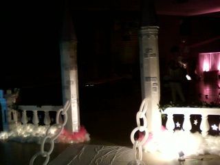 A balcony decorated with balloons and lights is lit up at night.
