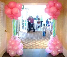 A hallway decorated with pink balloons and people walking in the background