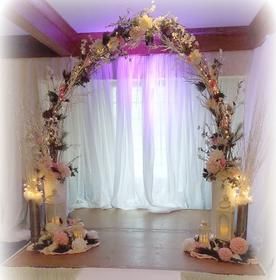 A room with a large arch decorated with flowers and lights.