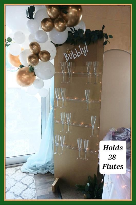 A wall filled with champagne flutes and balloons.