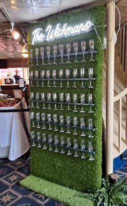 A wall filled with wine glasses and a neon sign.