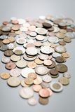 Pile of various coins, silver, copper, and gold, scattered on a gray surface.