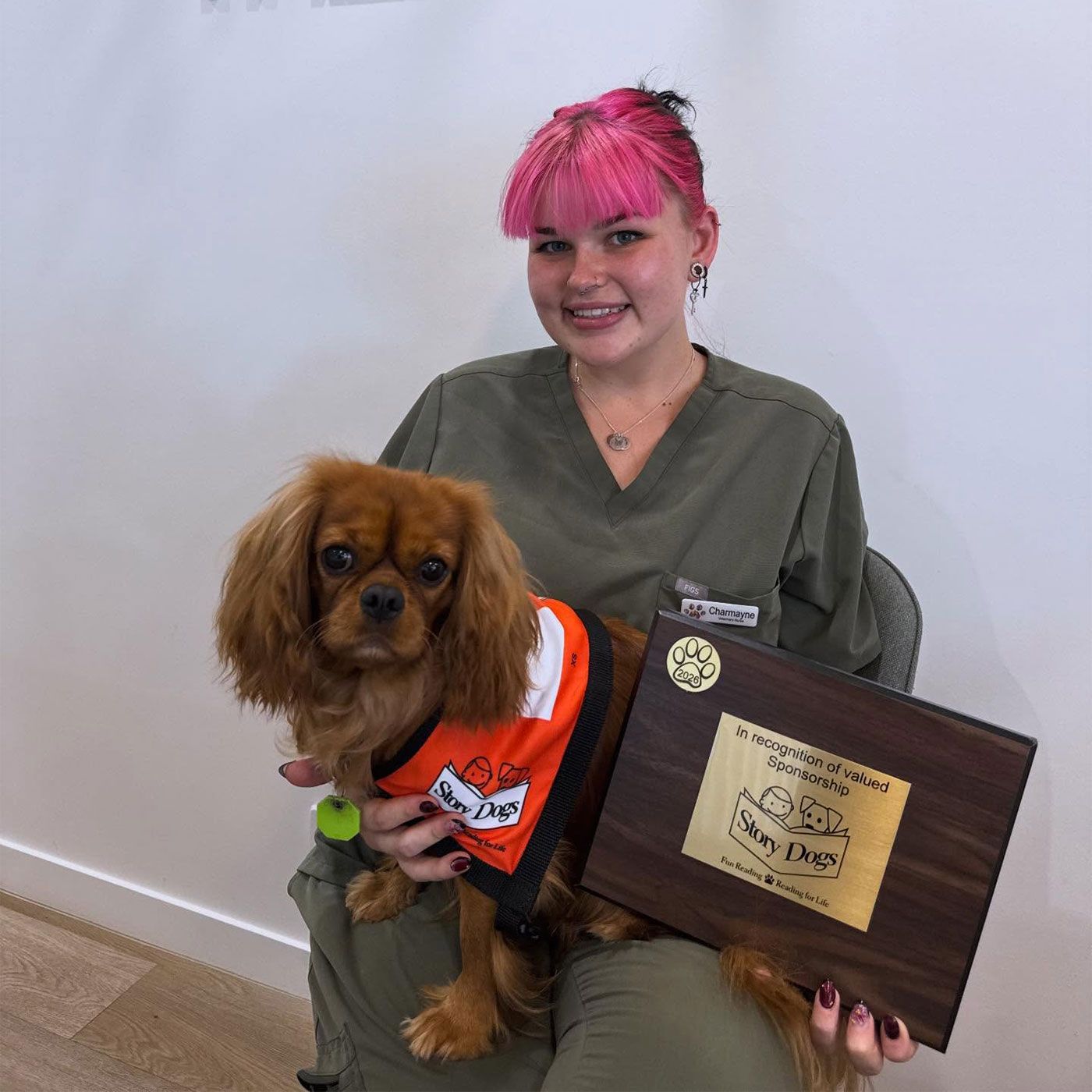 A Woman Holding a Small Dog in An Orange Vest — The Neighbourhood Vet in Tewantin, QLD