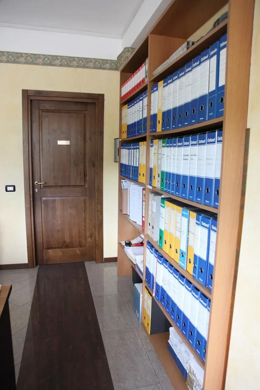 Corridoio con porta in legno e scaffali alti rivestiti di raccoglitori blu e bianchi