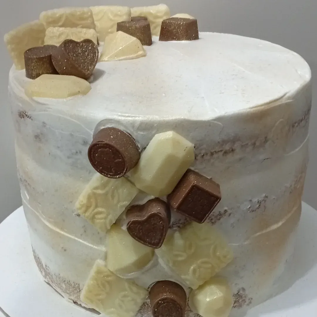 Pastel decorado con glaseado blanco y trozos de chocolate.