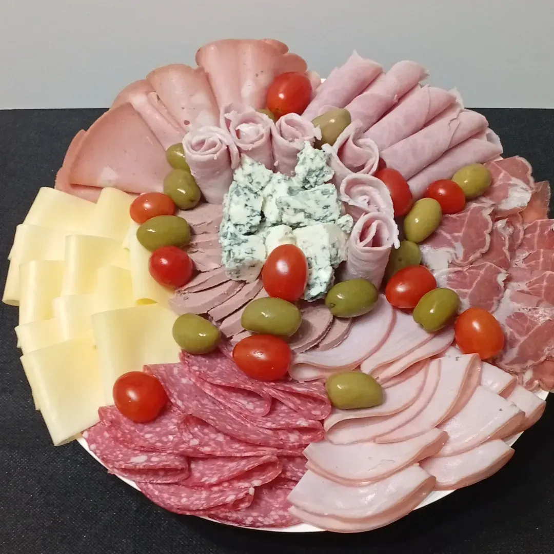 Tabla de embutidos con fiambres, quesos, aceitunas y tomates.
