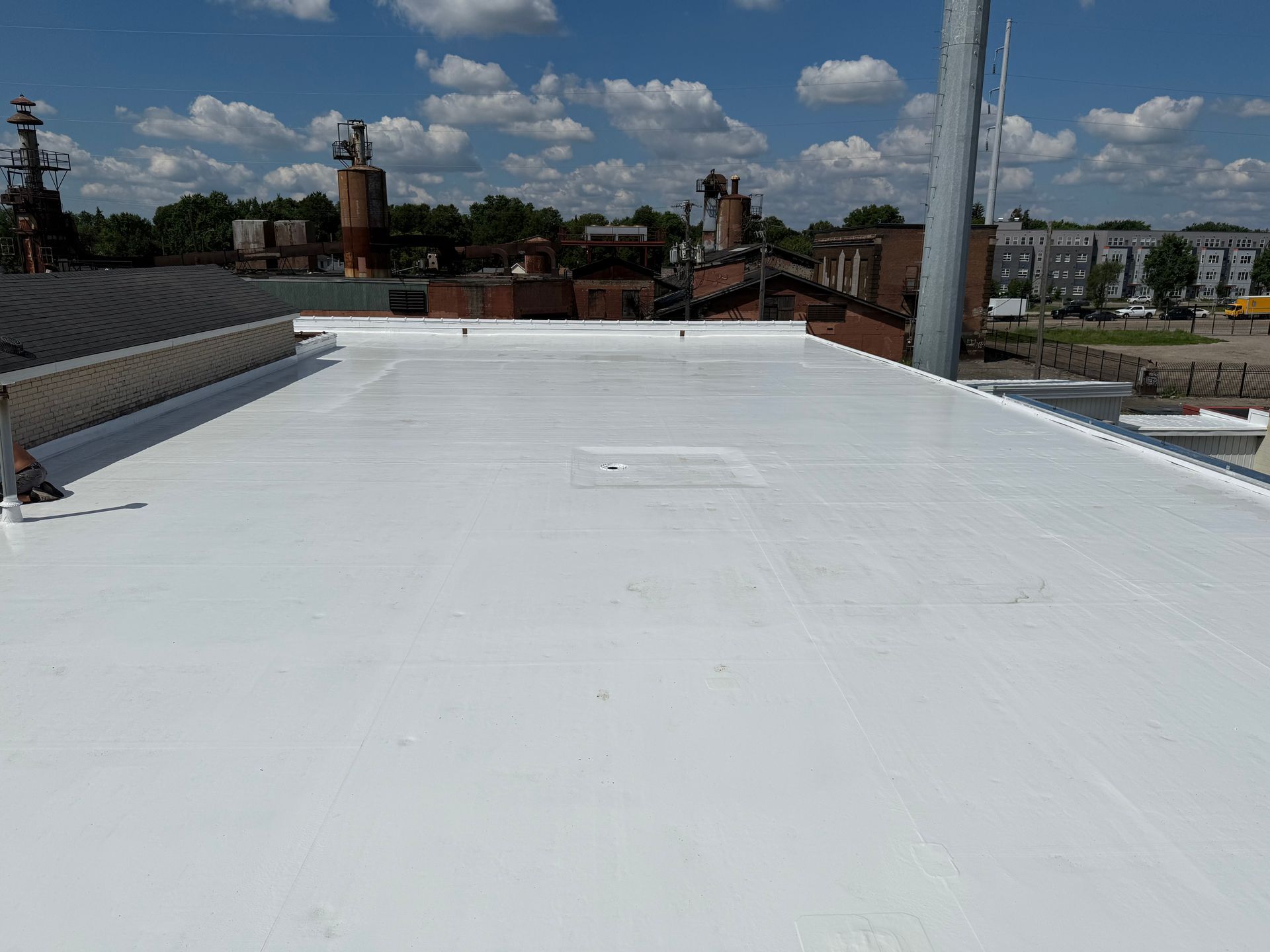 White flat roof overlooking industrial cityscape on a sunny day.