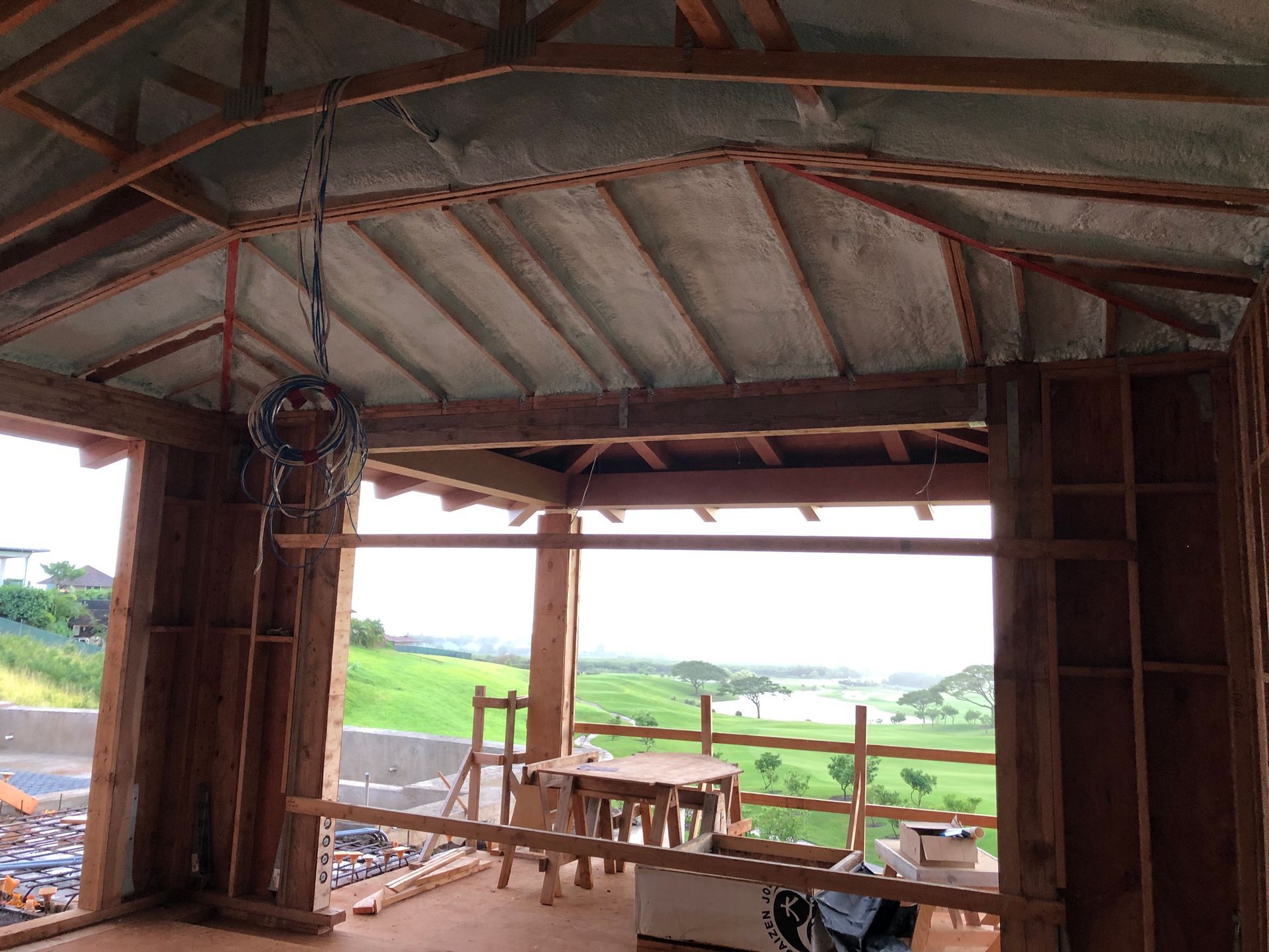 Wood-framed structure under construction, open to a scenic view, with insulation in ceiling.