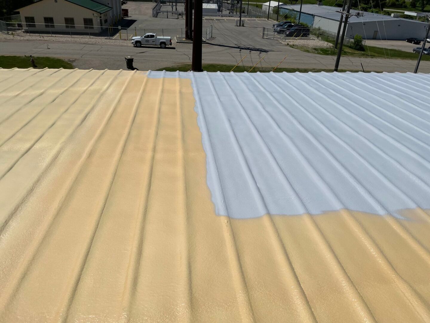 Metal roof partially painted yellow and white, outdoors with buildings visible in the background.